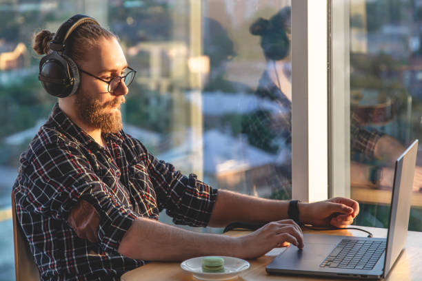 istock A man with a beard works at a computer, sitting in the office by the window. 1404727566