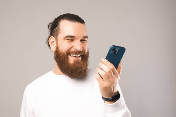 istock Close up photo of young bearded man talking on smarphthone via speacker 1404729122