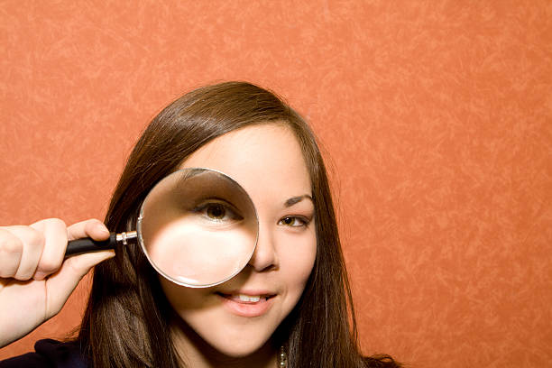 若い女性がカメラ目線で拡大鏡 - low scale magnification glass women holding ストックフォトと画像