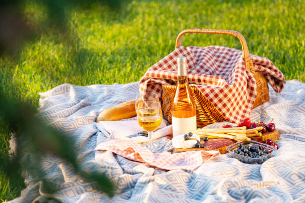 istock Picnic basket, wine, berries, jamon, cheese and bread are on the blanket. Picnic setting on a blanket in a meadow at sunset. 1404732134