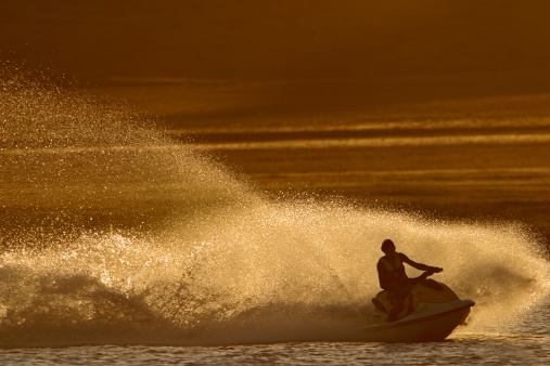 Backlit jet ski with water spray, late afternoon