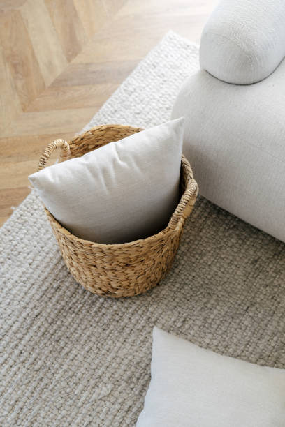istock Wicker basket with cushions standing on rug, near sofa 1404735271