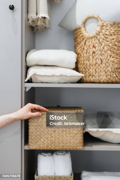 Housewife Puts Wicker Box With Clothes On Wardrobe Shelf Stock Photo - Download Image Now