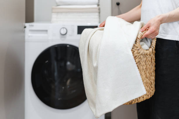 istock Woman with laundry basket standing against washing machine 1404735742