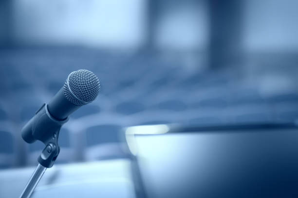 istock Rostrum with microphone and computer in conference hall with motion blur effect 1404735759