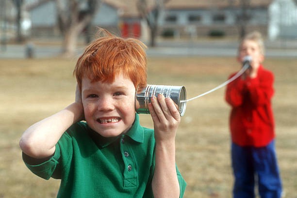 Two boys playing telephone with cans and string  stock photo