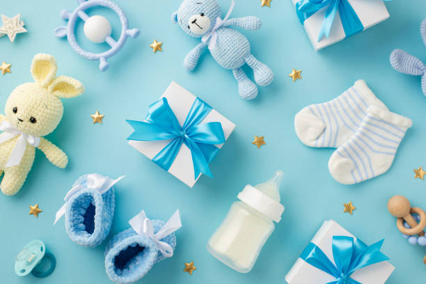 istock Baby accessories concept. Top view photo of gift boxes teether knitted bunny and teddy-bear toys socks shoes milk bottle rattle pacifier and gold stars on isolated pastel blue background 1404738325