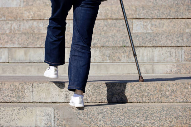 Woman wearing jeans with walking cane climbing stairs outdoor, legs in motion on the street steps stock photo