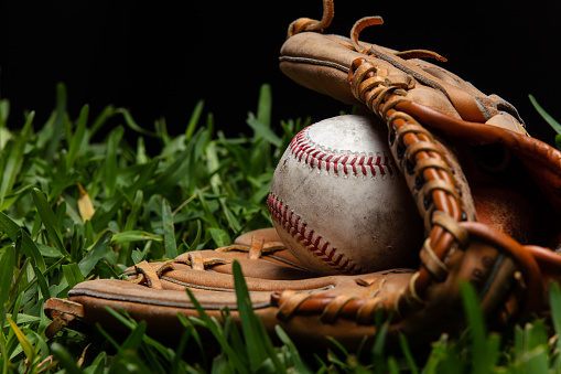 A baseball glove with a hand in it catches a fly ball against a blue sky background with plenty of room for copy space.