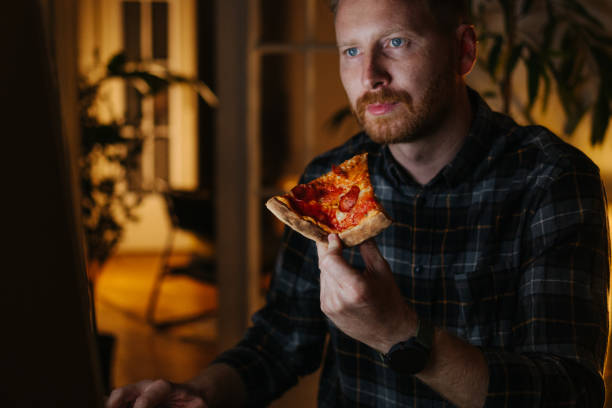 istock A Serious Ginger Businessman Eating Pizza While Working Night Shift From Home Using His Computer 1404741304