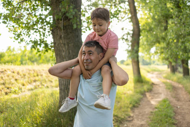 Family carrying son on shoulders stock photo
