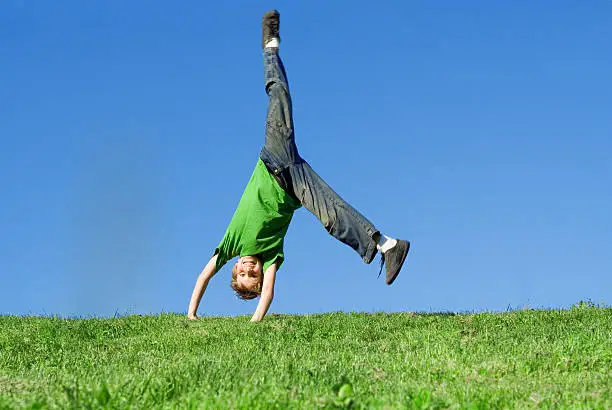 happy child doing handstand on hilltop