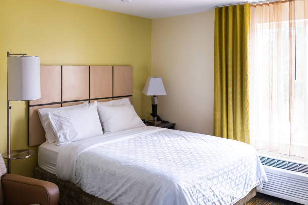 ランプライト付きのベッドルームルーム、マットレスベッドのヘッドボードにシート付きの白い枕、誰もいないモダンなホテルのモーテルルーム、窓のカーテンエアコン - bedroom hotel hotel room inn ストックフォトと画像