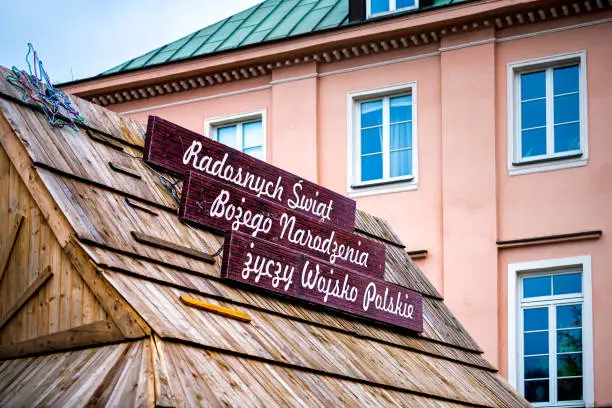 Sign in Polish language reading Happy Holidays of God's nativity wishes from Polish army on building wooden roof during Christmas winter holiday in Warsaw, Poland