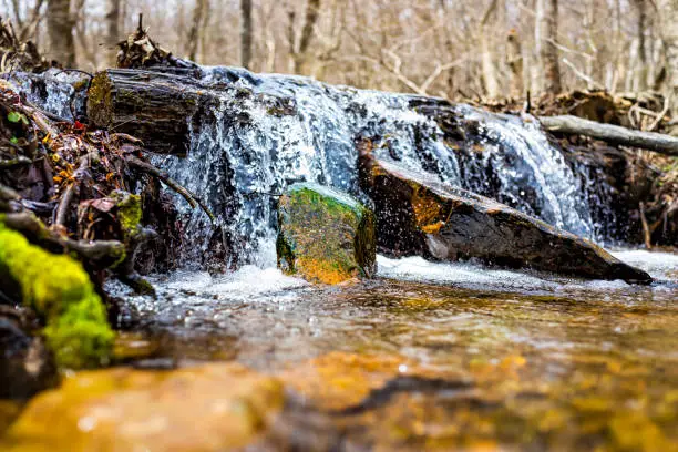Photo of Small waterfall river stream water flowing in Shamokin Springs Nature preserve hiking trail in Wintergreen Resort in Virginia closeup low angle ground level view