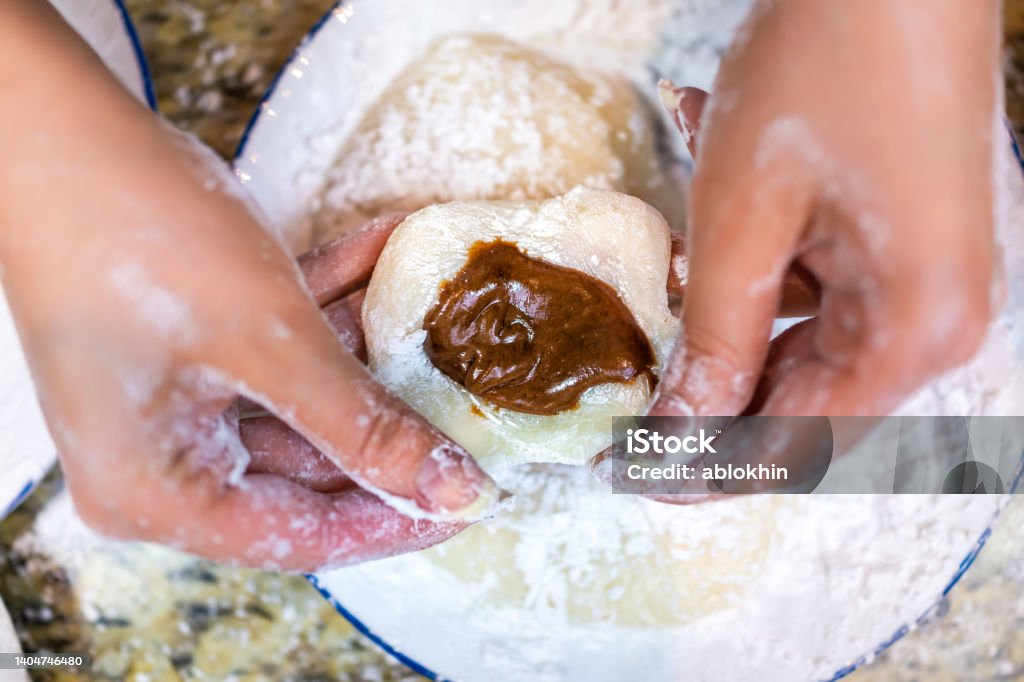 Flat top view of hands shaping cooking making mochi sticky daifuku Japanese rice cake with chocolate filling and starch flour as traditional dessert Mochi Stock Photo