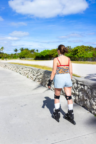 フロリダ州サウスビーチのオーシャンドライブでオーシャンウォークボードウォークで歩く若い女性のバックローラースケート、フロリダ州サウスビーチのオーシャンドライブ、保護膝手パ� - 16315 ストックフォトと画像