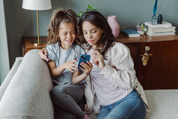 istock Young mom and smiling little daughter using smart phone at home 1404747500