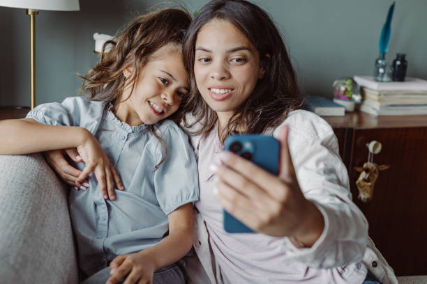 istock Mom and smiling little daughter using smart phone at home 1404747501