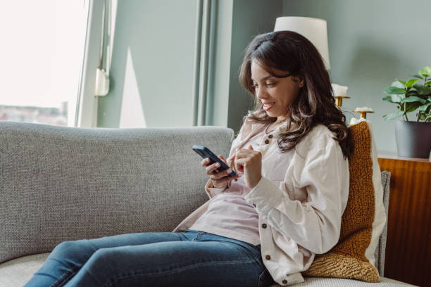 istock Young woman using mobile phone at home. Scrolling through social media 1404747687