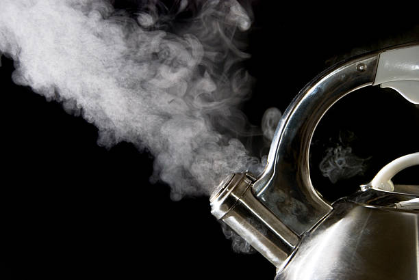 istock Tea kettle releases steam and boils water on black backdrop 140474820