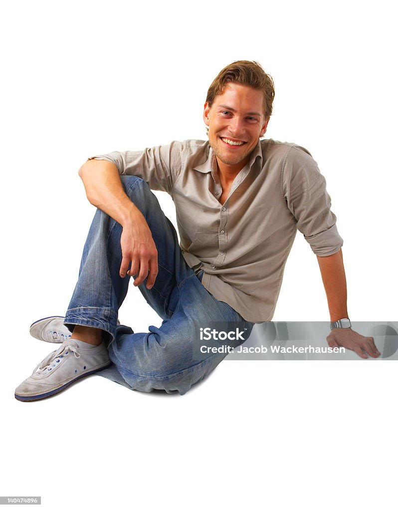 Felice giovane uomo seduto e sorridente - Foto stock royalty-free di 20-24 anni