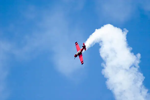 Red acrobatics plane performing a roll against a blue sky
