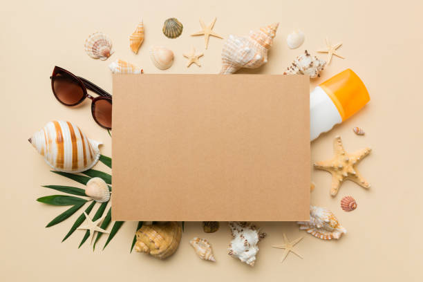 istock Summer time concept with blank greeting card and blank craft paper on colored background. Seashells from ocean shore in the shape of frame separated with space for text top view 1404753390