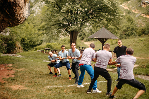 Men having fun on a picnic pulling rope