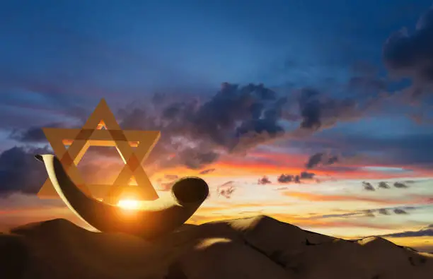 Shofar of ram's horn traditionally used for Jewish religious purposes,  Yom Kippur and Rosh Hashanah; beautiful sunset sky with sunburst in bachground