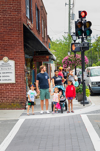 Blowing Rock, NC, USA-20 June 2022: Biracial couple with children crossing Sunset Drive at Main St. Busy sidewalk behind.