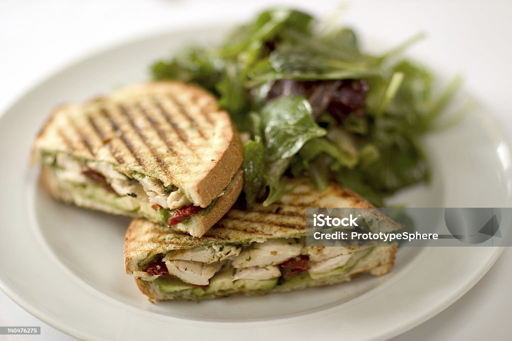 Chicken Panini Two Chickaen panini sandwich on a white plate.  A mixed green salad on the side.  Shallow depth of field. Panini Stock Photo