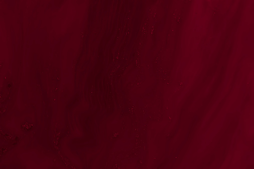 Abstract beautiful art effect of dark red maroon colour swirls added to milk to create an interesting image background pattern.