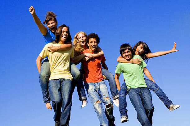 group of happy diverse teens or youth playing piggyback race stock photo