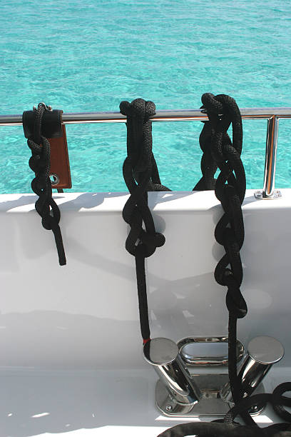 Black ropes tied on chrome rail of boat stock photo