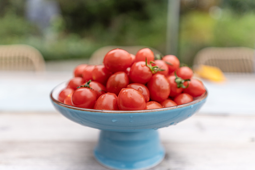 A plate of red cherry tomato on a wooden table