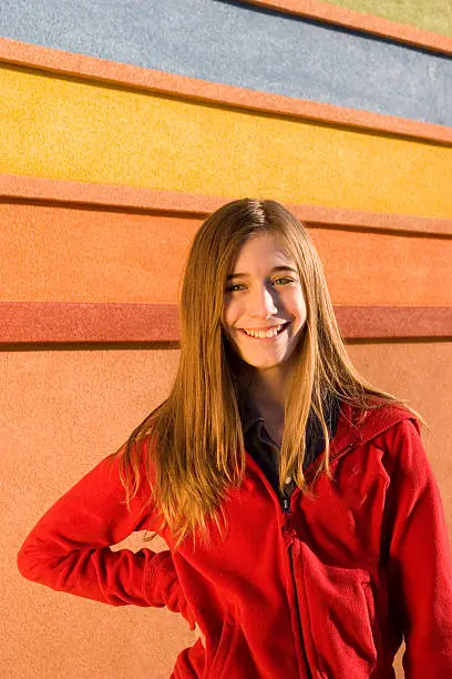 Happy girl, smiling in front of a background.  