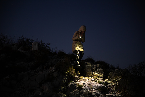 Person With hand Light Descending from a Mountain Afternoon Hike With Caution