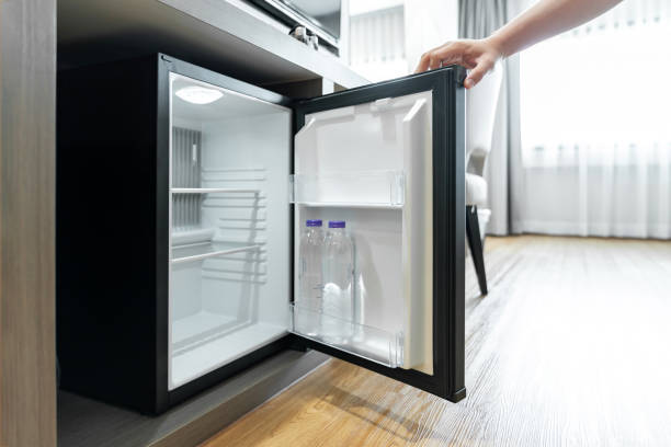 istock Man Hand opened mini small refrigerator and reached drinking plastic water bottle under the wood counter in the hotel resort bedroom. 1404773469
