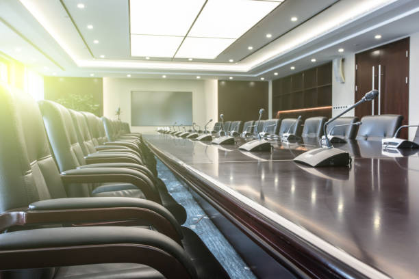 istock Empty meeting room with big wooden table, leather seats, microphone and big screen 1404775502
