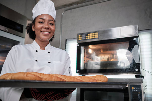 istock Professional female chef with baking bread, cheerful smile in the kitchen. 1404778157
