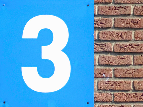 A Brick wall of a warehouse, and a plate, with the number three printed on it. Photo shot in Dusseldorf, Germany, on early June, 2022