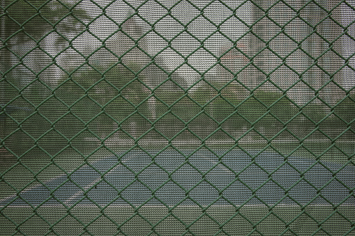 A green steel net that snags the fence of the tennis court.