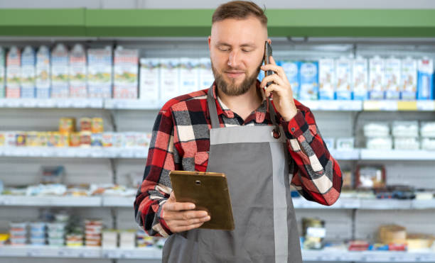 istock Professional supermarket clerk using a touch screen tablet and working, smiling at camera, supermarket worker ordering goods by phone, man food store assistant at work, Retail 1404797004