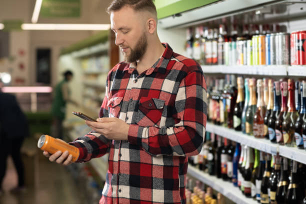 shopping in wine department of supermarket, handsome man choosing beer in can, bearded guy standing near shelves with alcohol, buying alcohol shopping in wine department of supermarket, handsome man choosing beer in can, bearded guy standing near shelves with alcohol, buying alcohol concept grocery shelf cans stock pictures, royalty-free photos & images