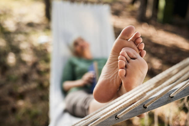 Feet of children, which swinging on hammock at summer. Kids enjoying, boys dreaming resting together under tree. Happy childhood. High quality