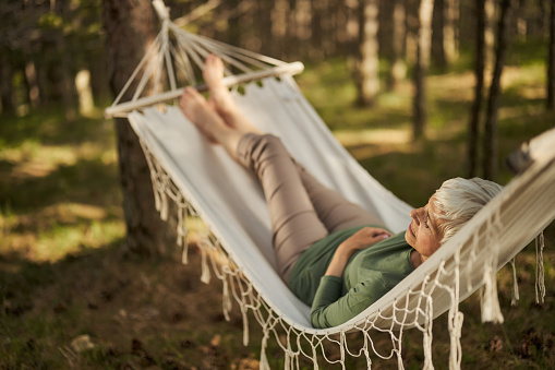 Serene mature woman sleeping in hammock in nature.