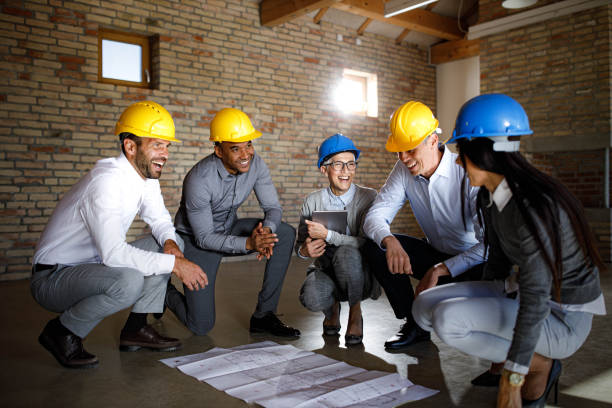 istock Group of happy architects talking while going through plans in the office. 1404800881