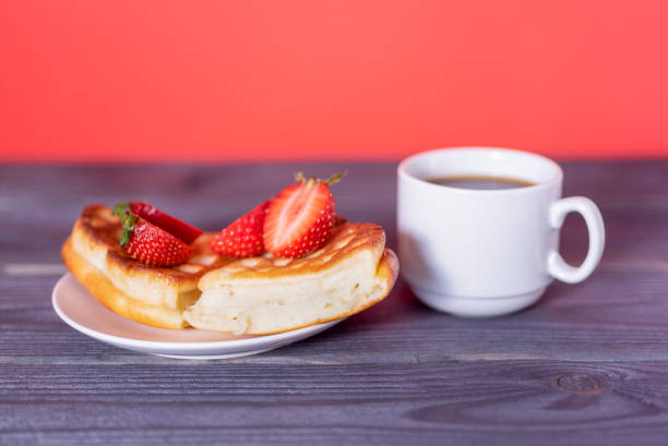 Belgian waffles with strawberries and coffee on a wooden, dark table. The concept of a delicious breakfast.
