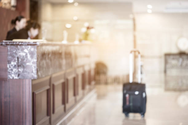 Woman with suitcase ringing hotel service bell with welcome drink and sea and palm tree view on sunset. Travel concept. 24-hour beach hotel front desk. Late check-out.